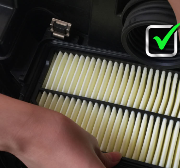 Hands installing a rectangular air filter into a compartment, with a green check mark in the corner.